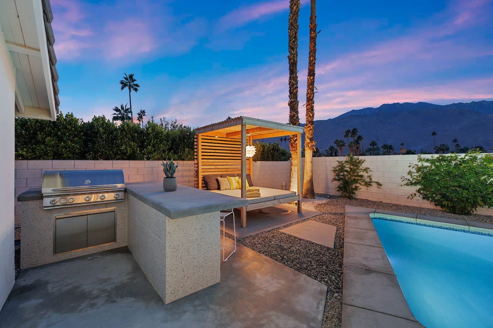 The built-in gas grill and bar, steps from the pool and the shaded cabana daybed.