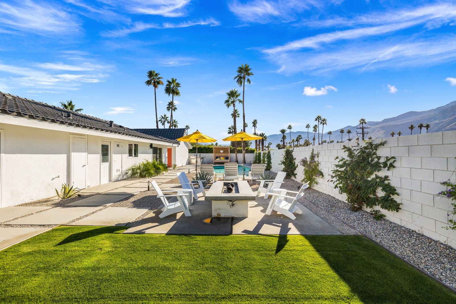 The lawn and fire pit, with the pool just beyond. Room for kids to run while the grown-ups settle into the Adirondack chairs.
